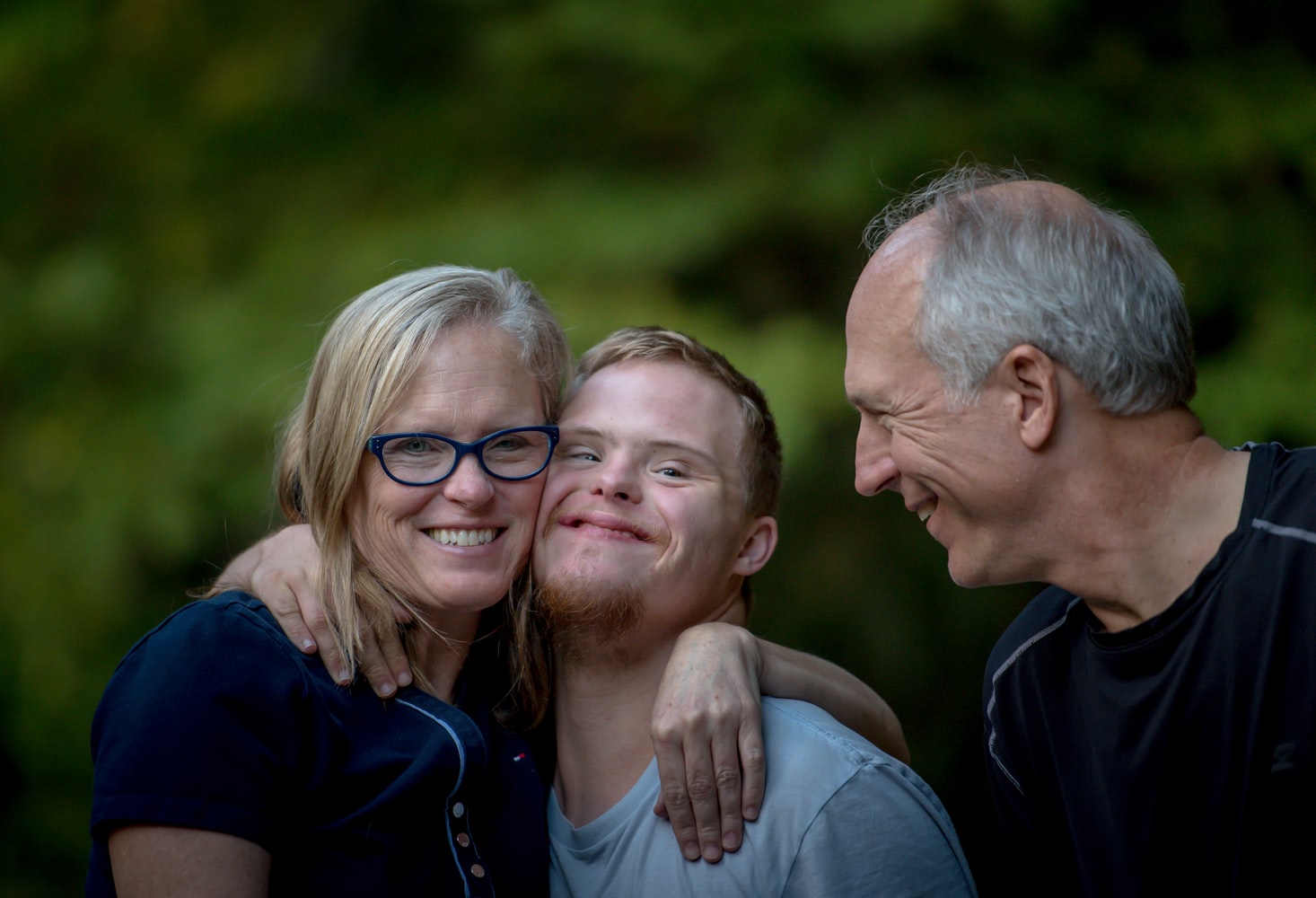 mother father and disabled son hugging