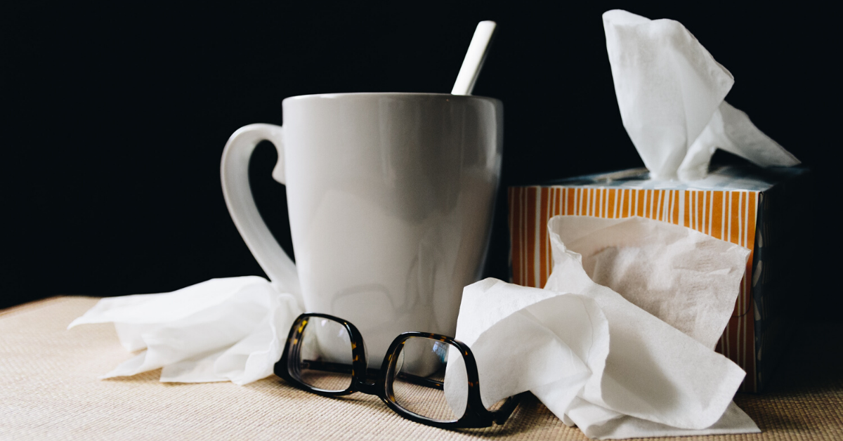 a cup of tea, glasses, and tissues on a table